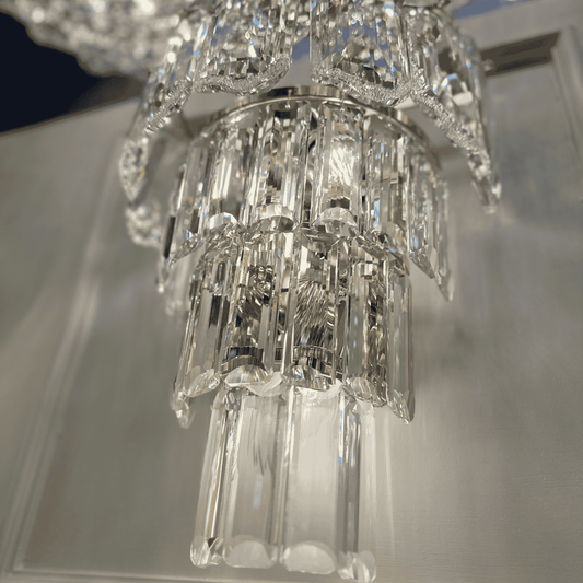 Detailed close-up of a tiered crystal wall sconce light with reflective clear glass prisms.