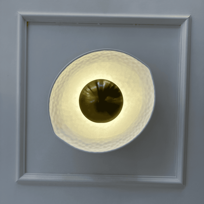 Decorative deco wall sconce with white hammered shade and golden reflective center viewed from the front.