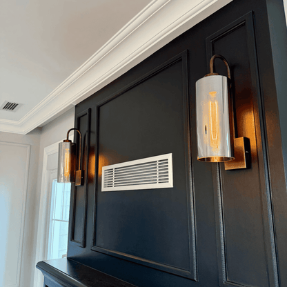 Two blown glass wall sconces with antique mounts on a dark paneled wall.