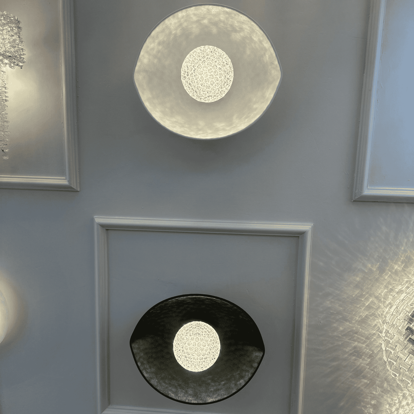 A symmetrical setup of black and white plexiglass LED sconces mounted on a paneled wall emits soft ambient light.