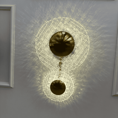 Entryway wall sconce with brass and clear glass design emitting layered, warm lighting.