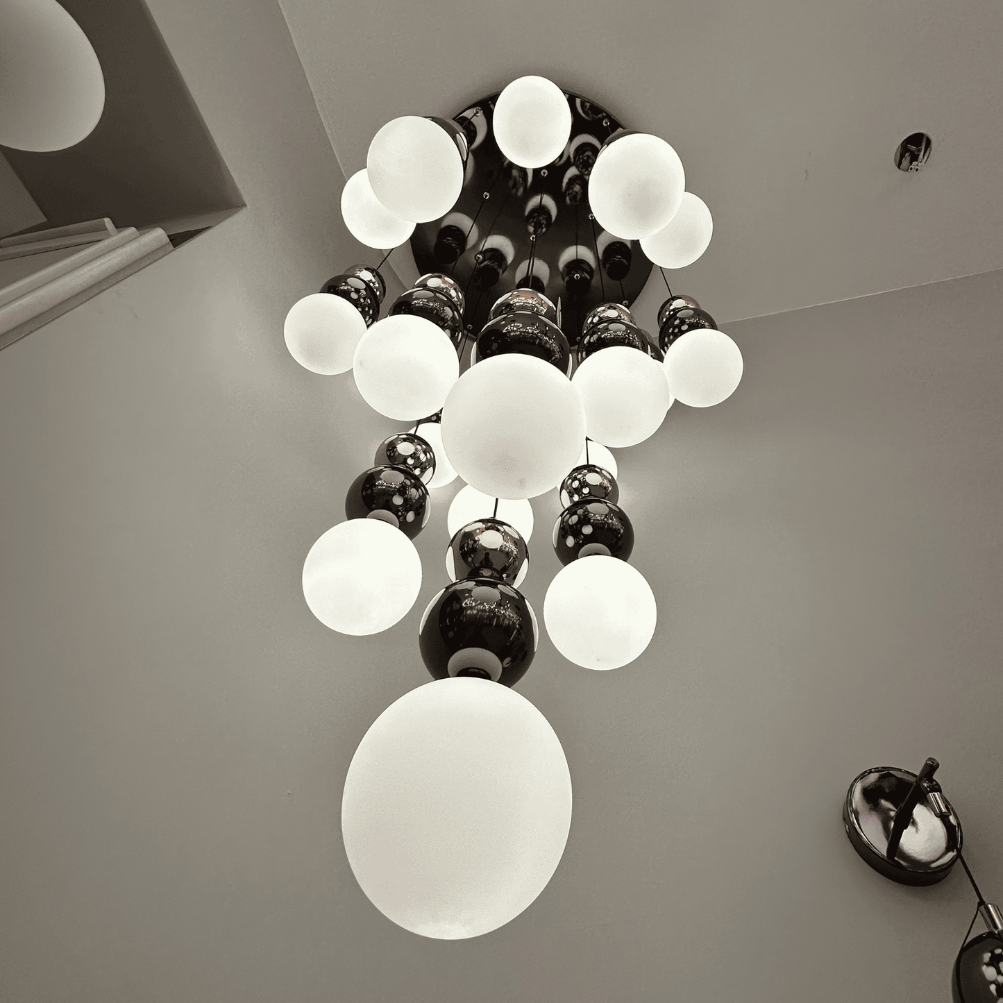 Upward view of a modern frosted glass globe pendant lighting fixture in a cascading chandelier design.