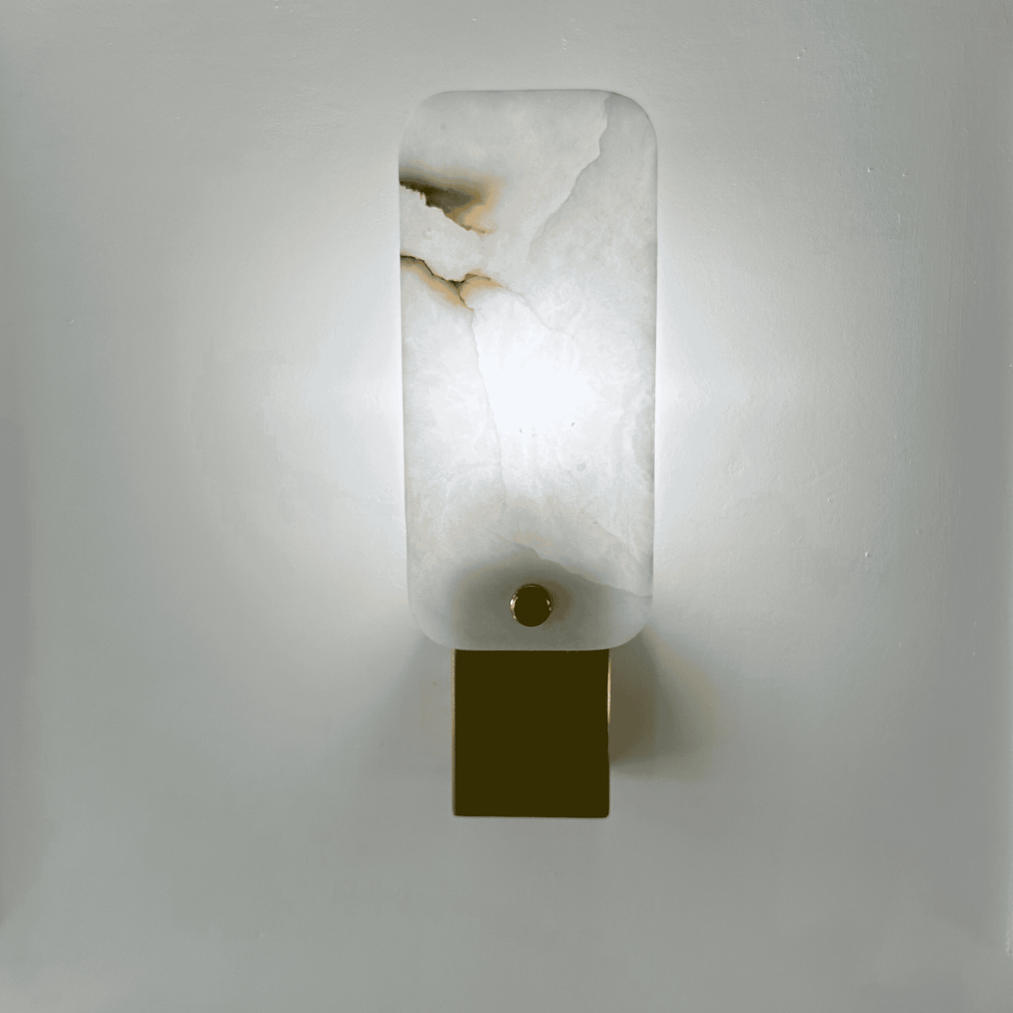 Glowing white square marble wall lamp with soft light and brass detail.
