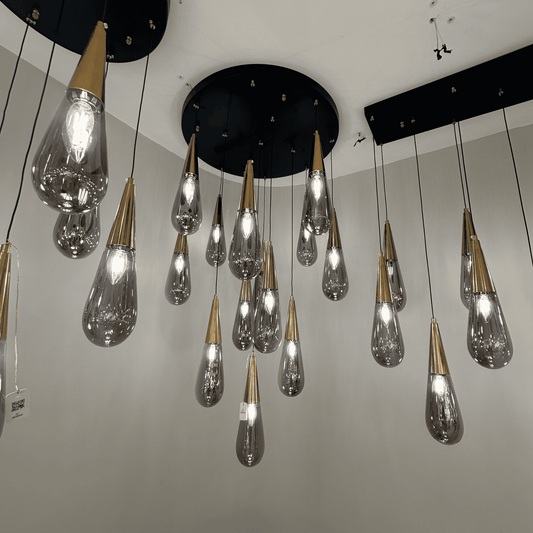 Gold-top teardrop pendant lights suspended from a black ceiling base for elegant modern interiors.