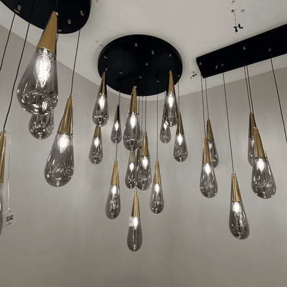 Gold-top teardrop pendant lights suspended from a black ceiling base for elegant modern interiors.