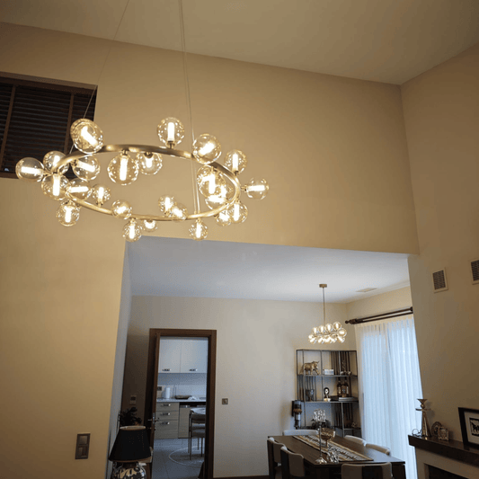 High-ceiling modern chandelier featuring a brass ring and clear globe bulbs in a spacious interior.
