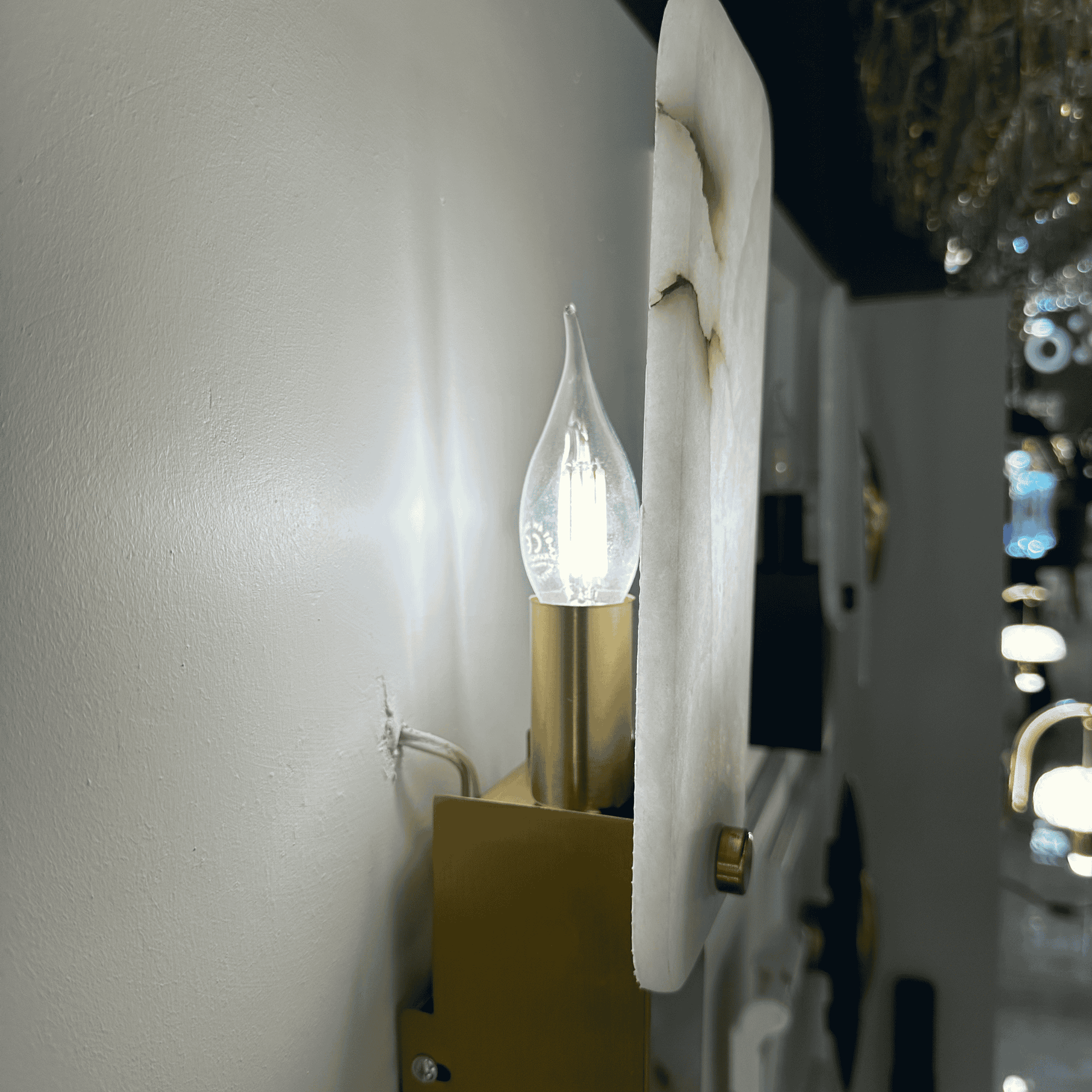 Illuminated marble wall lamp with brass holder and visible LED bulb behind the white stone shade.