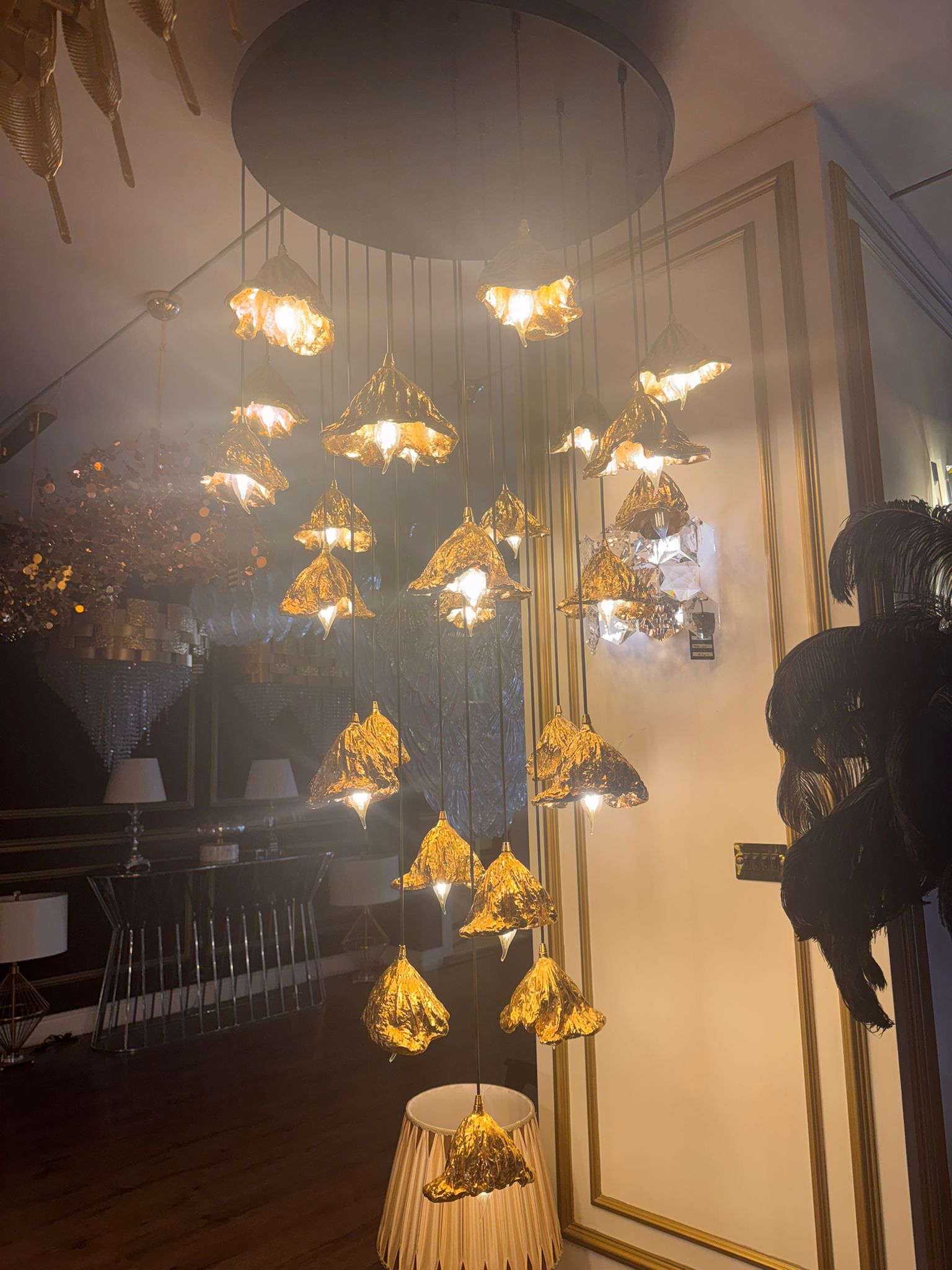 Illuminated pure brass leaf pendant chandelier glowing in an upscale showroom.