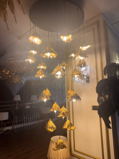 Illuminated pure brass leaf pendant chandelier glowing in an upscale showroom.