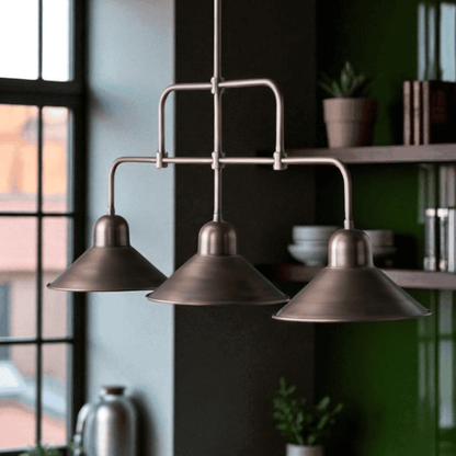 Triple-shade bronze industrial pendant light hanging in a modern kitchen with green shelving and natural light.