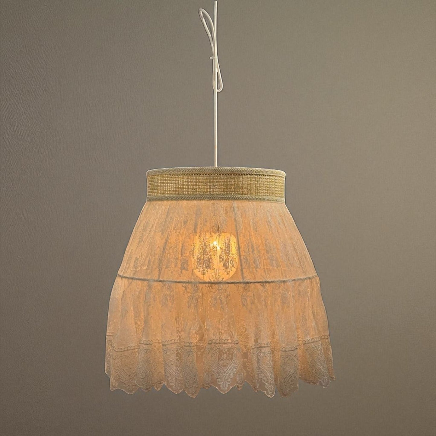Lace pendant light above a traditional bed setting, casting soft light in a romantic bedroom interior.