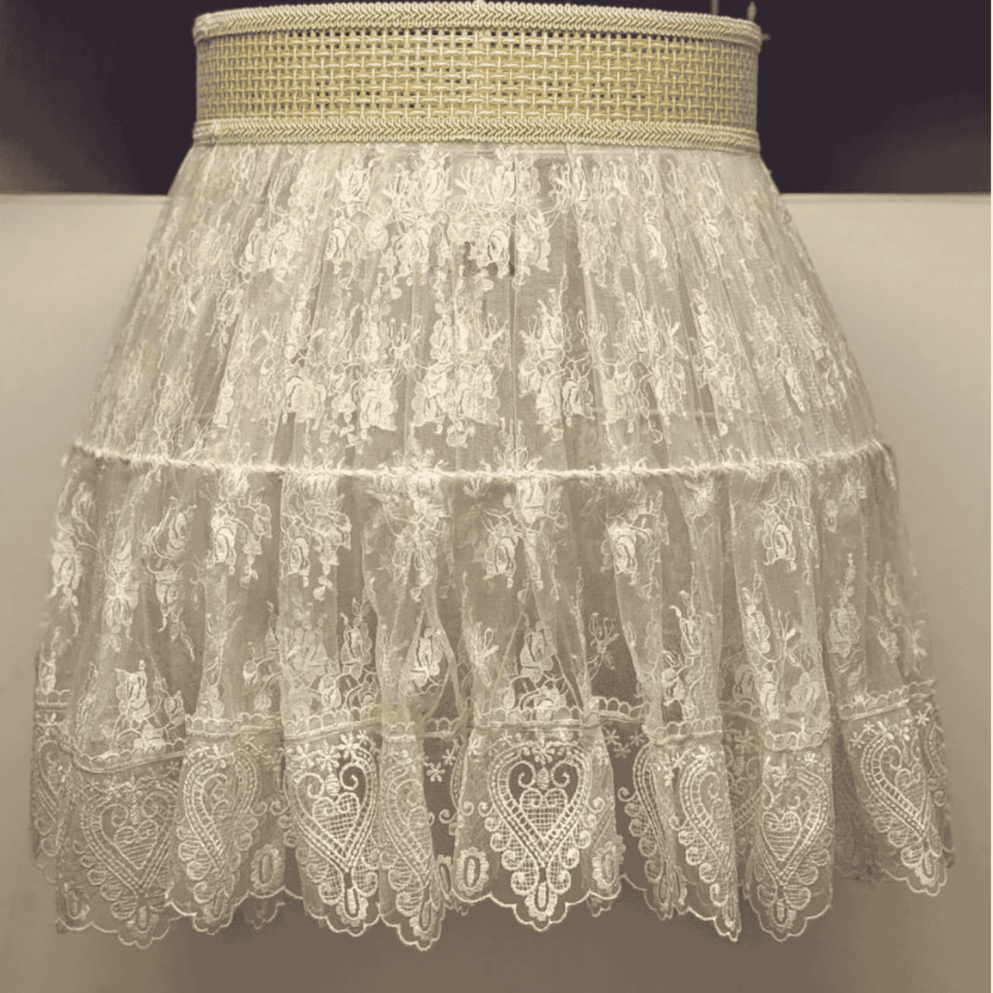 Close-up of a vintage-style lace pendant light with sheer floral embroidery and woven trim for elegant boho lighting.