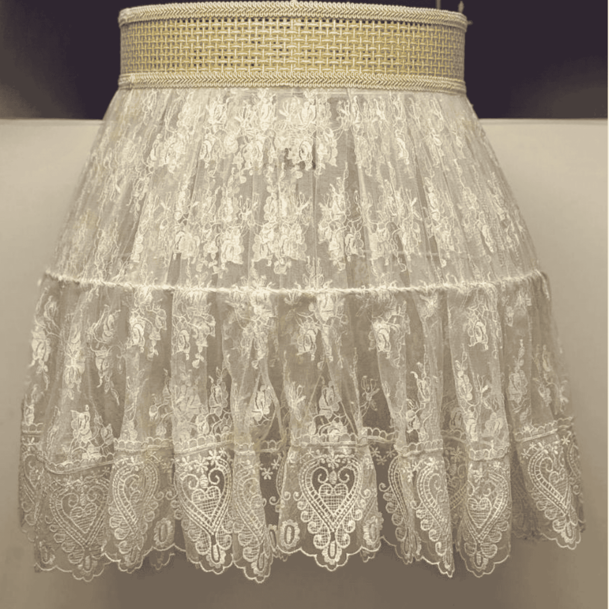 Close-up of a vintage-style lace pendant light with sheer floral embroidery and woven trim for elegant boho lighting.