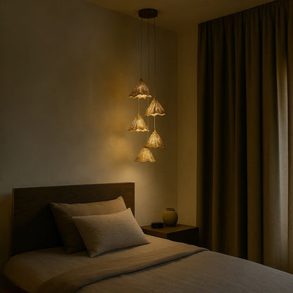 Gold leaf pendant lights hang beside a bed, casting a warm and ambient glow ideal for modern bedroom lighting design.
