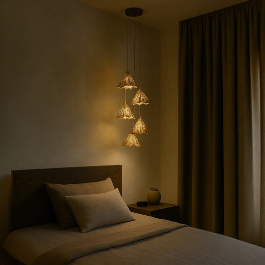 Gold leaf pendant lights hang beside a bed, casting a warm and ambient glow ideal for modern bedroom lighting design.