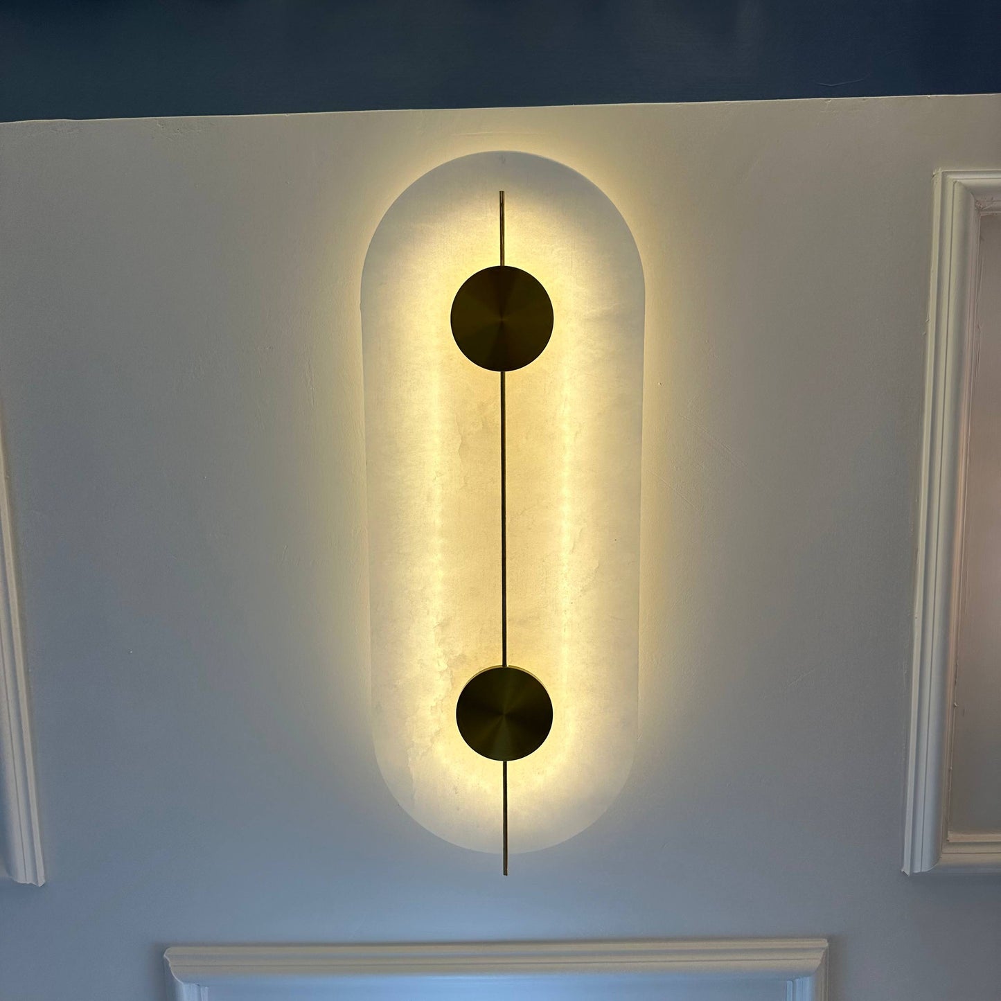 Wall-mounted luxury alabaster light fixture with brass accents and ambient glow.