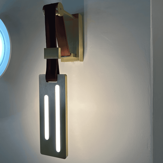 Dual vertical LED leather wall sconce with brushed brass base for luxury lighting decor.