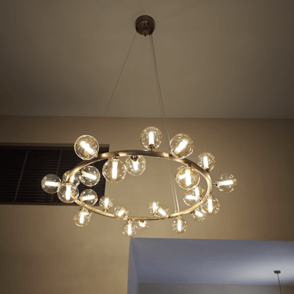 Modern brass chandelier with LED bulbs inside glass globes, suspended from the ceiling with minimal cables.