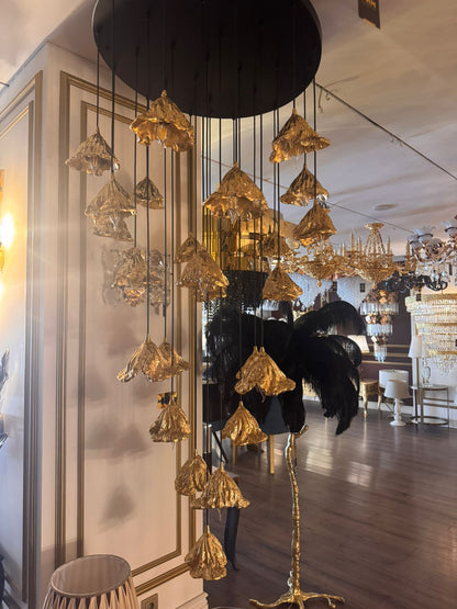 Cascading pure brass leaf pendant lights on display in an upscale lighting showroom.