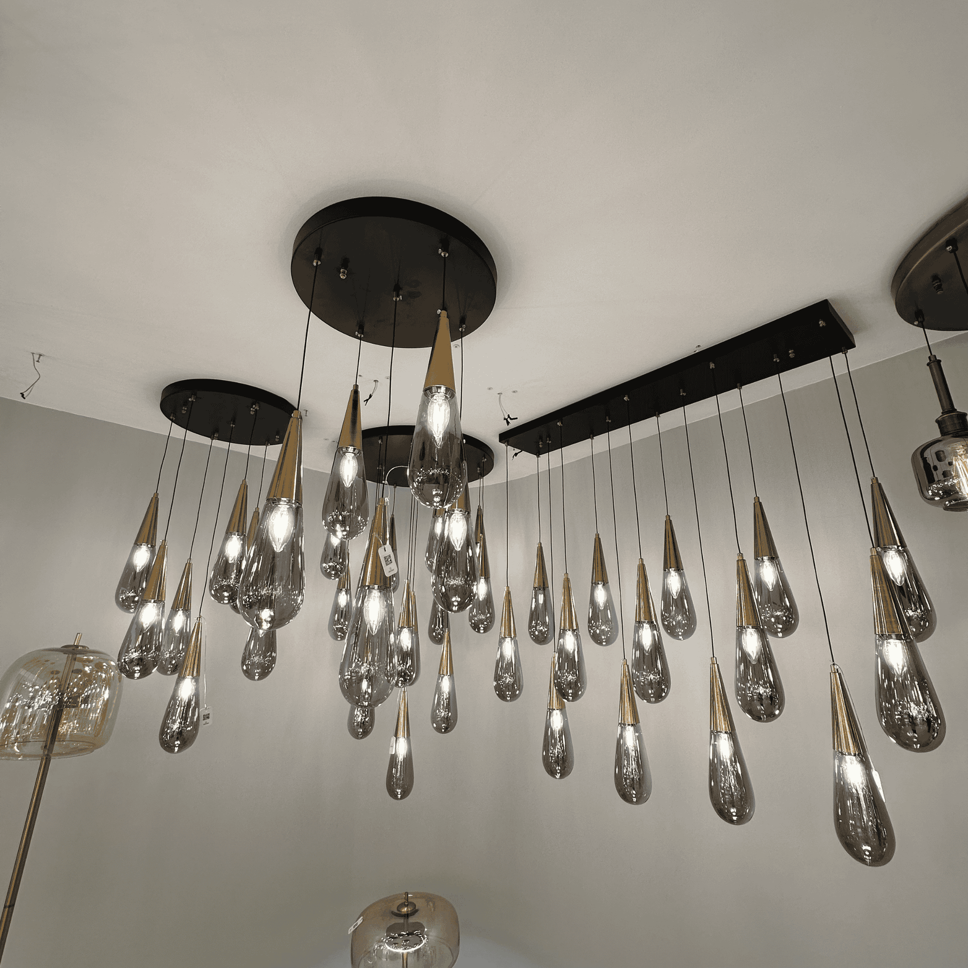 Luxury pendant light installation with gold-coned teardrop glass shades suspended from black ceiling mounts.