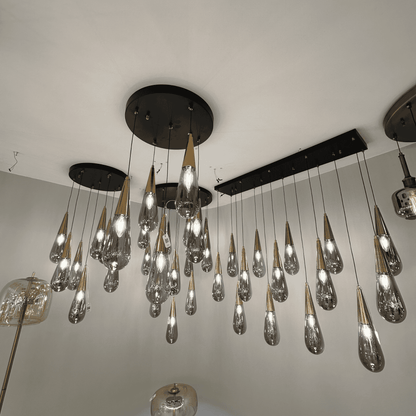 Luxury pendant light installation with gold-coned teardrop glass shades suspended from black ceiling mounts.