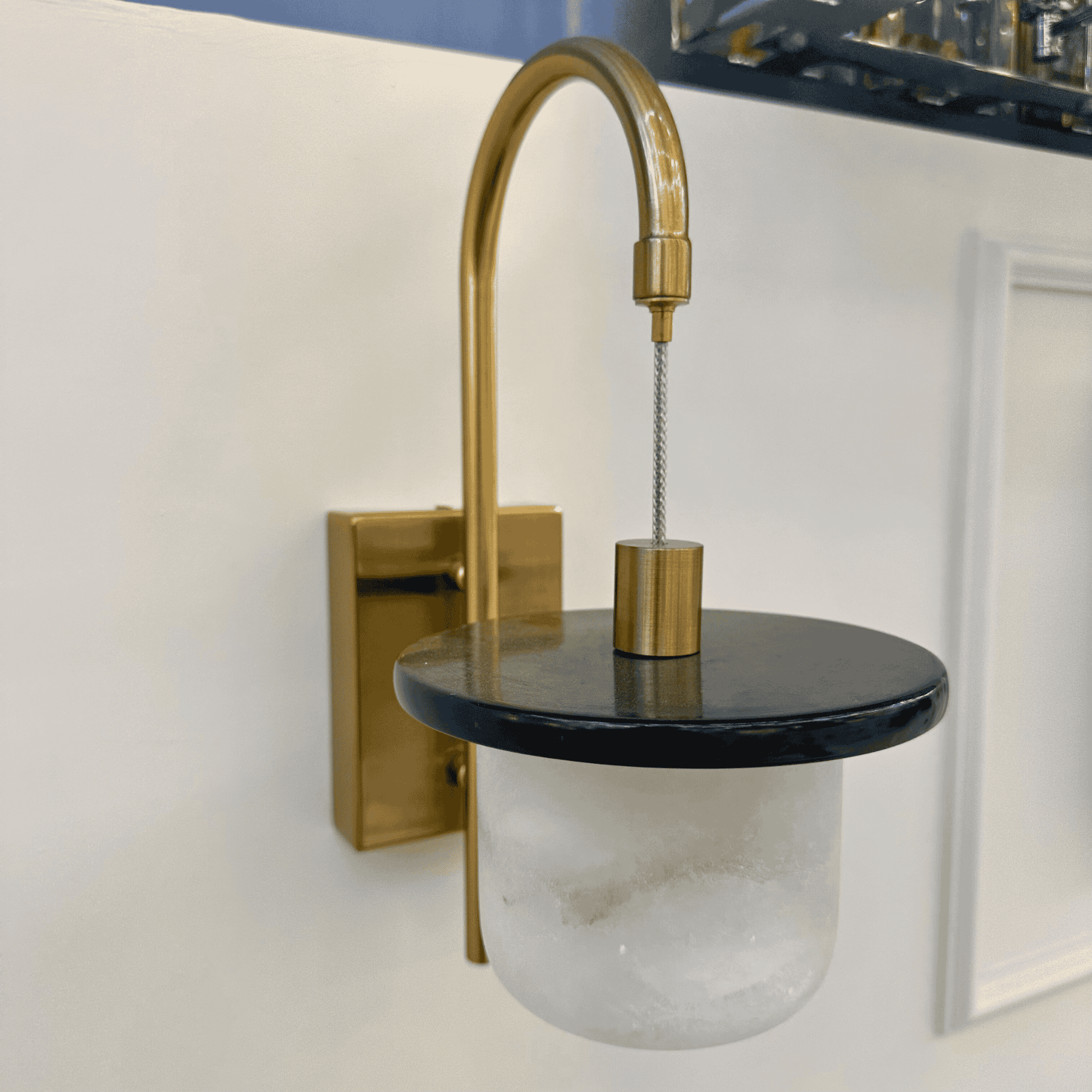 Side angle of marble sconce wall light with alabaster shade and brass frame.