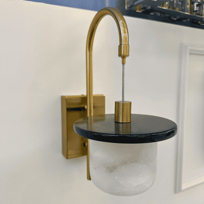 Side angle of marble sconce wall light with alabaster shade and brass frame.