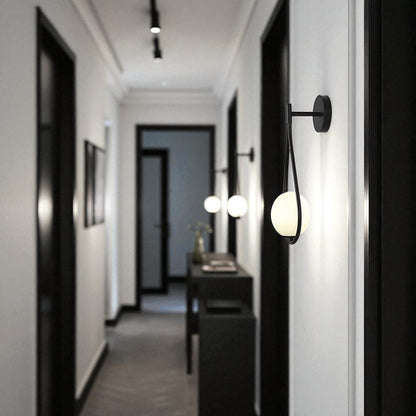 Modern matte black teardrop wall sconces lighting up a contemporary hallway with white walls and dark trim.