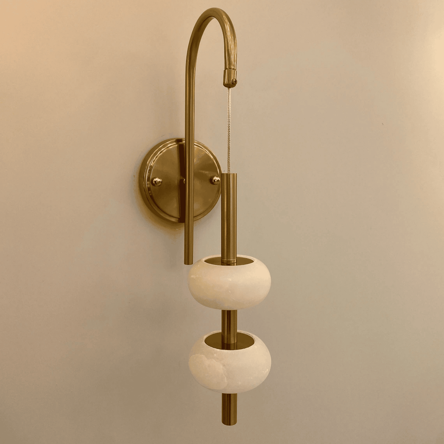 Unlit brass wall light with two alabaster rings in a clean, minimalistic modern style.