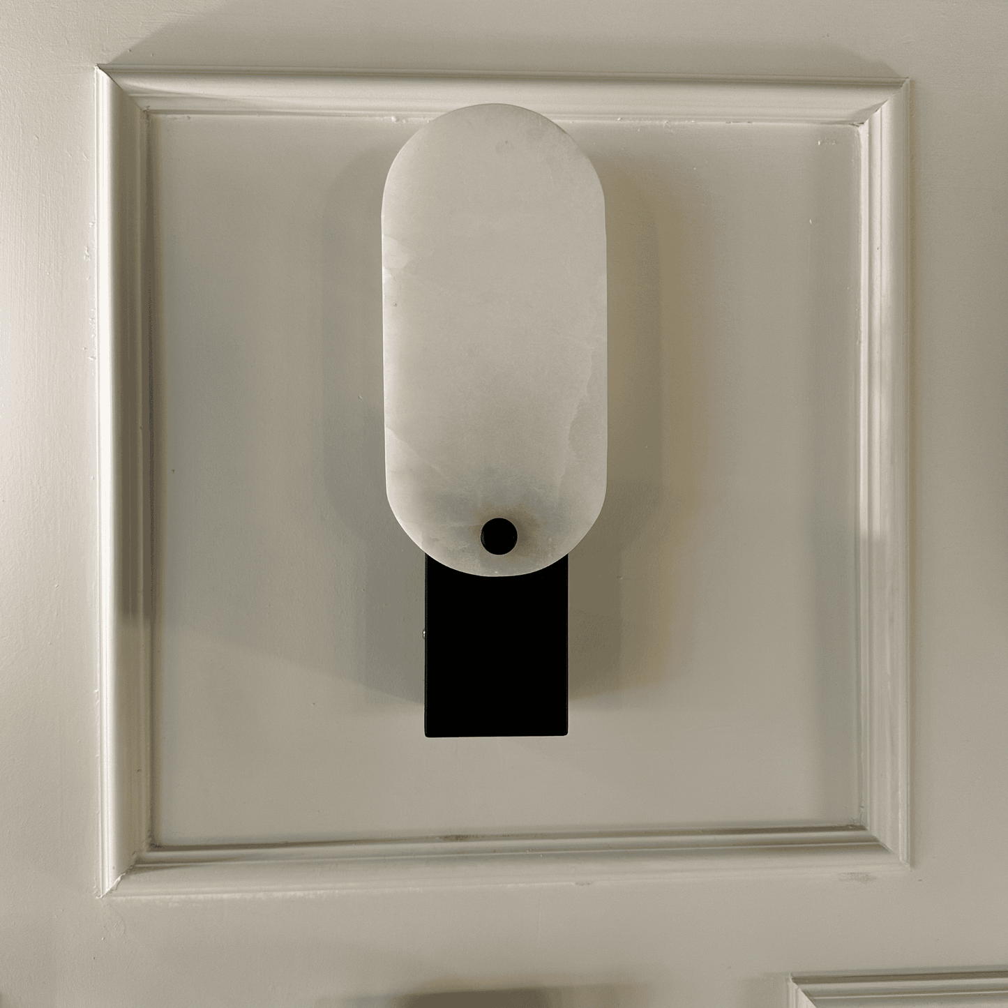 Minimalist black and white square marble wall lamp mounted on framed wall.