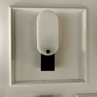 Minimalist black and white square marble wall lamp mounted on framed wall.