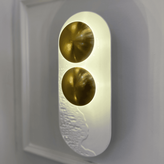Close-up of white resin and brass minimalist LED wall sconce ideal for modern interiors.