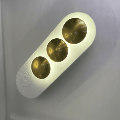 Triple-disc minimalist LED wall sconce with white resin body and brass details for modern interiors.