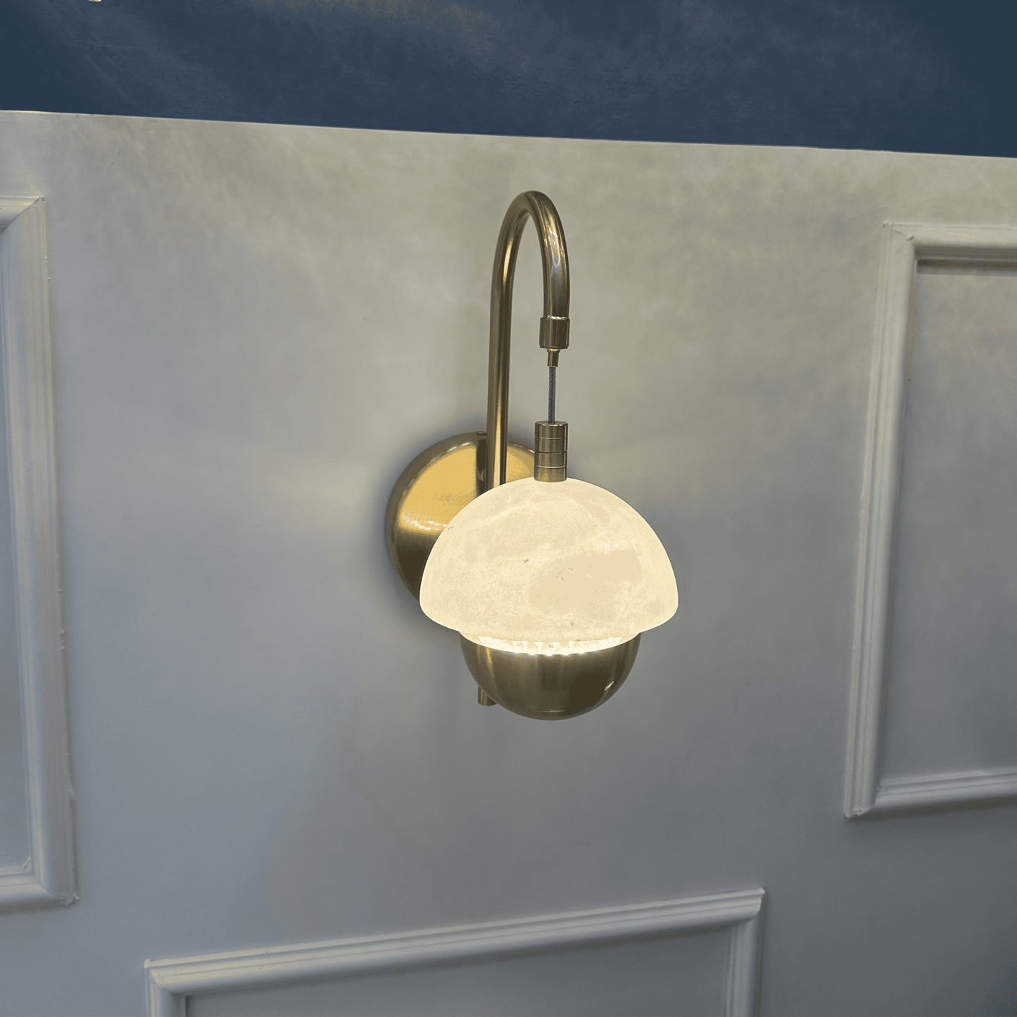 Brass and marble sconce with minimal design on a neutral wall.