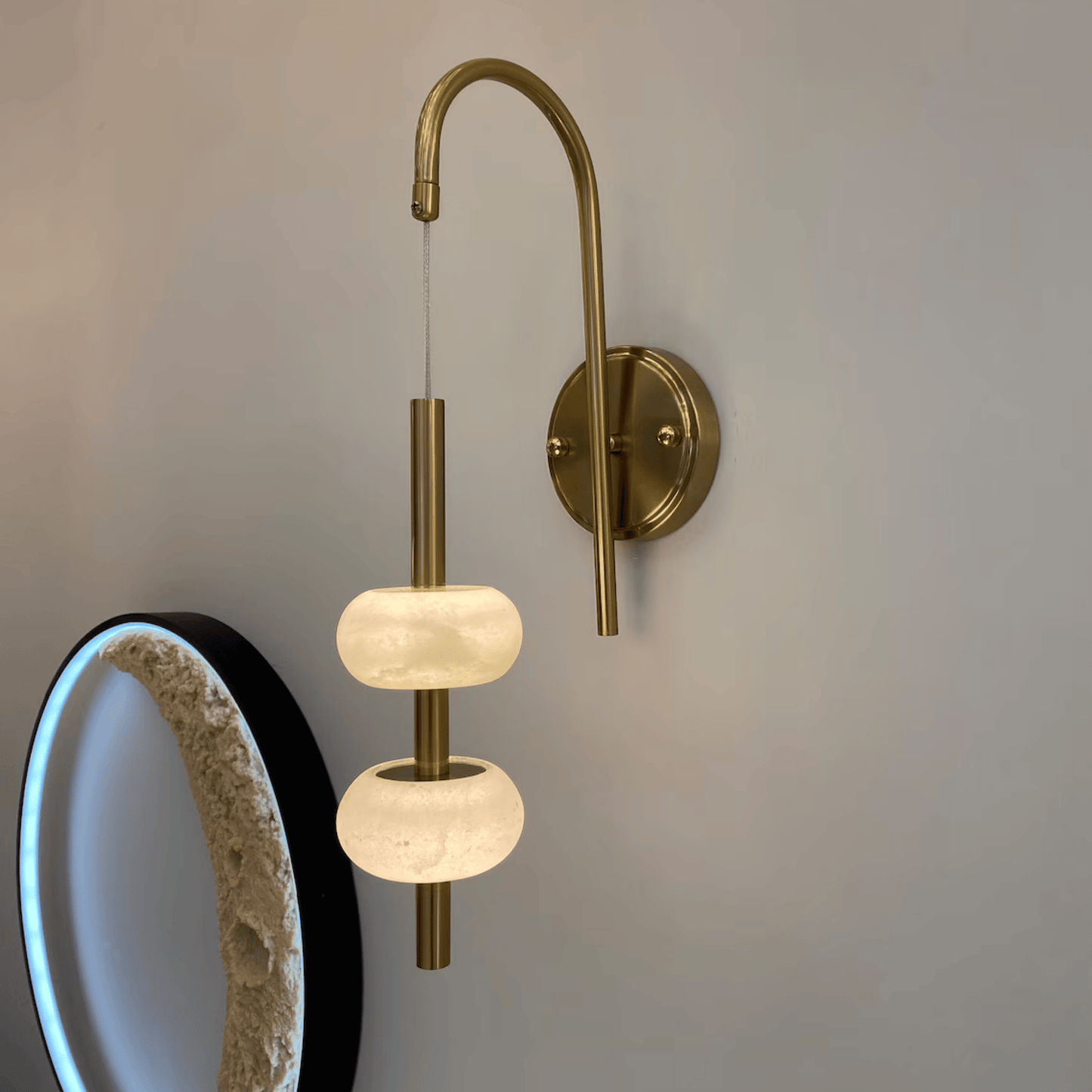 Brass wall light with twin alabaster shades mounted on a curved arm for modern interior lighting.