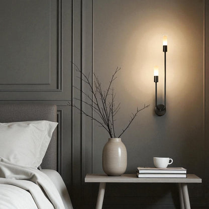 A sleek black wall sconce with dual vertical LED lights illuminates a modern bedroom wall, enhancing the minimalist decor with soft ambient lighting.