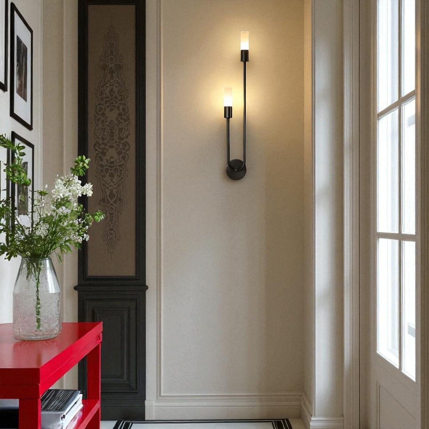 Modern wall sconce on a neutral wall with a red console table and decorative elements.