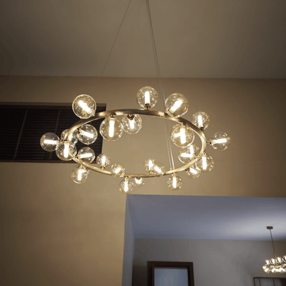 Brass ring chandelier with clear glass globes suspended from the ceiling, providing warm modern ambient lighting.