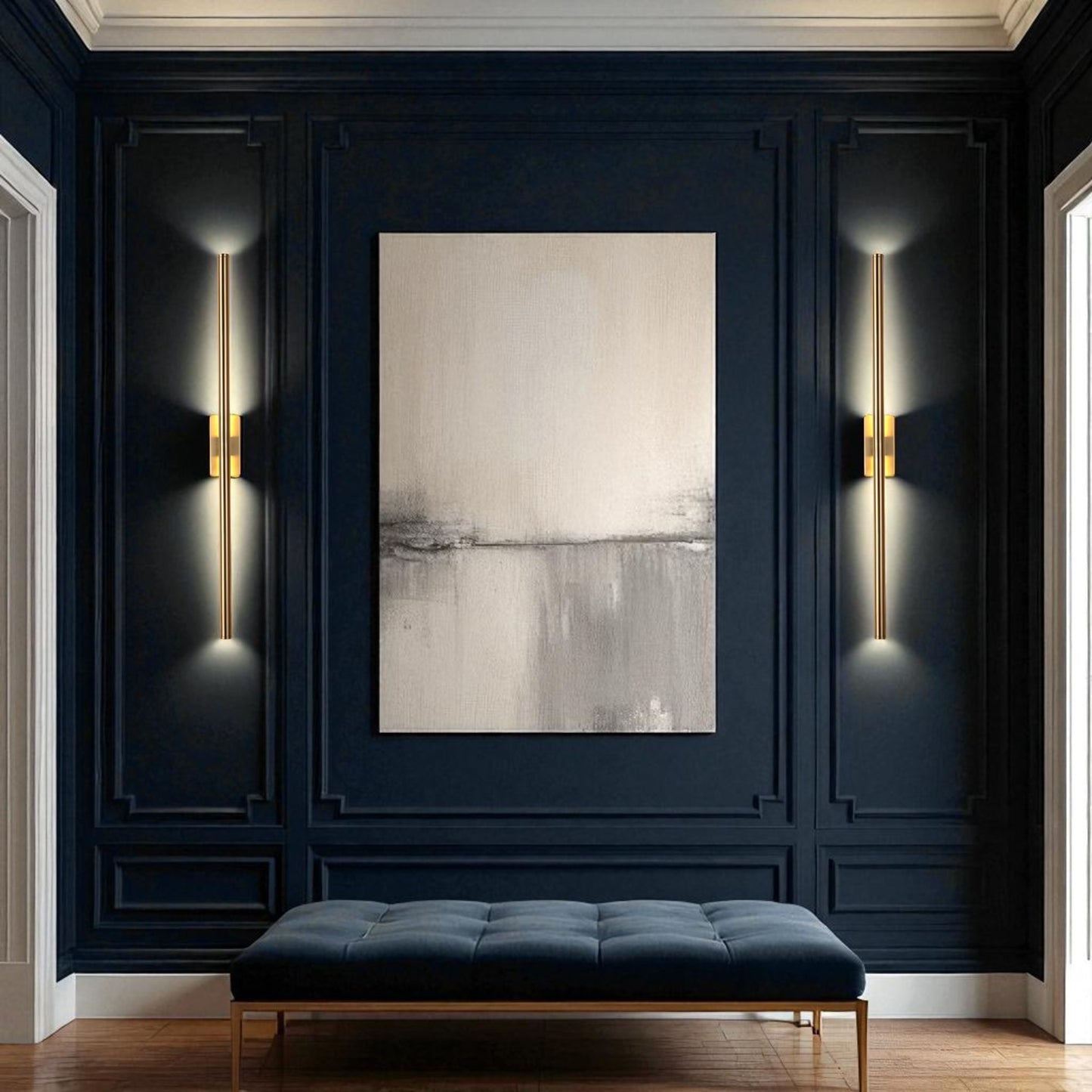 Modern brass wall sconces on dark navy paneled walls with a minimalist painting and bench in a contemporary entryway.