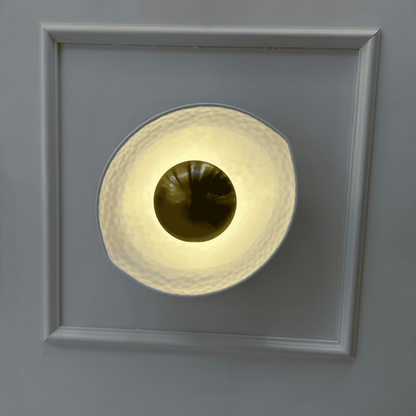 Front view of a white and gold deco wall sconce with a hammered finish and golden dome, emitting soft ambient light.