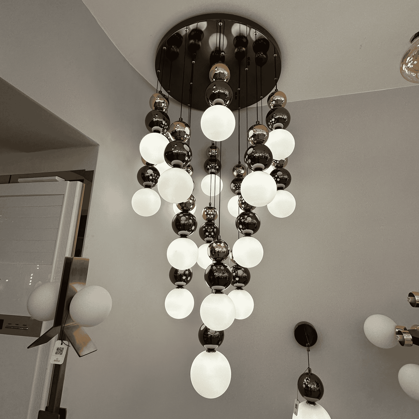 A modern pendant light with frosted and metallic glass globes arranged in a tiered cascade, perfect for staircase lighting.