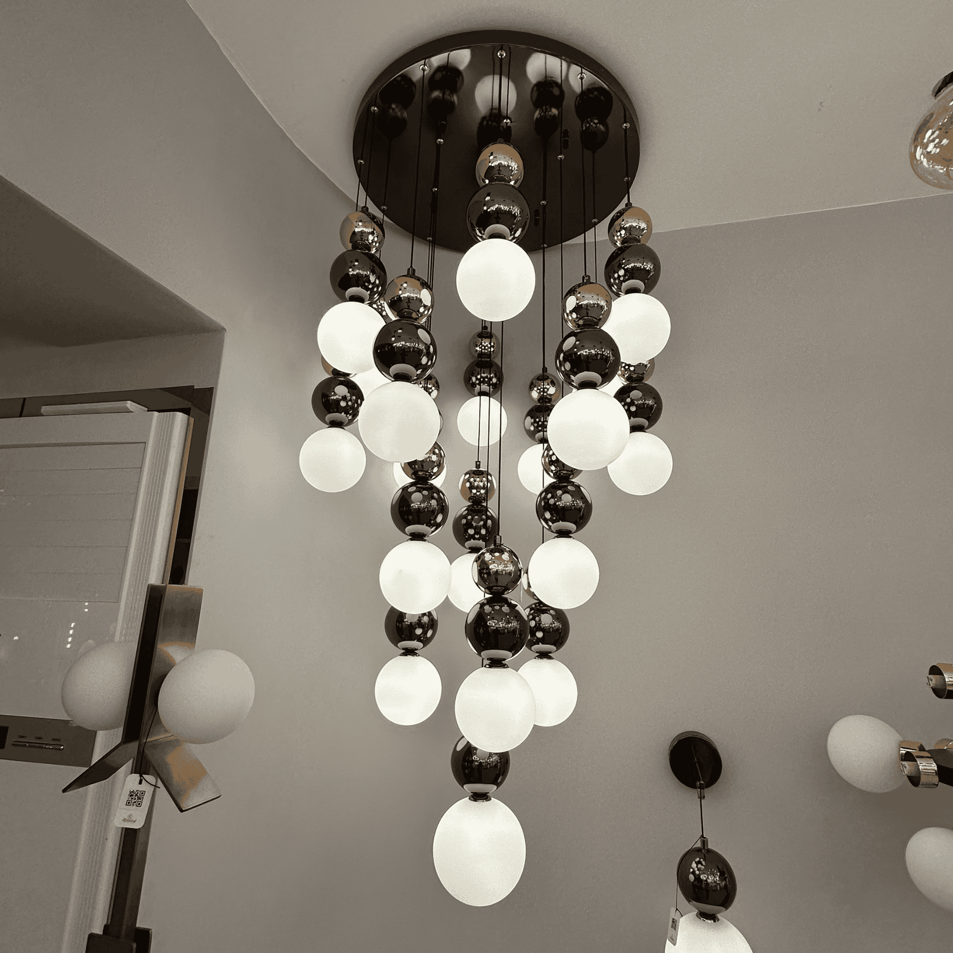 A modern pendant light with frosted and metallic glass globes arranged in a tiered cascade, perfect for staircase lighting.
