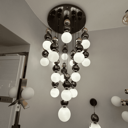 A modern pendant light with frosted and metallic glass globes arranged in a tiered cascade, perfect for staircase lighting.