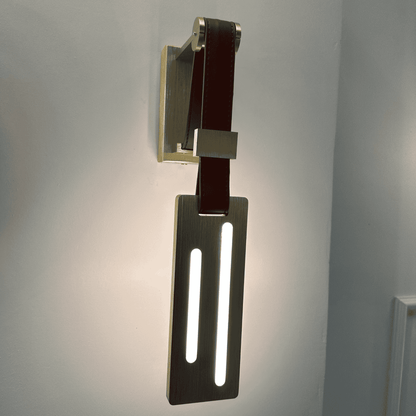 Modern leather wall sconce with vertical LED strip lights mounted on a brushed brass plate
