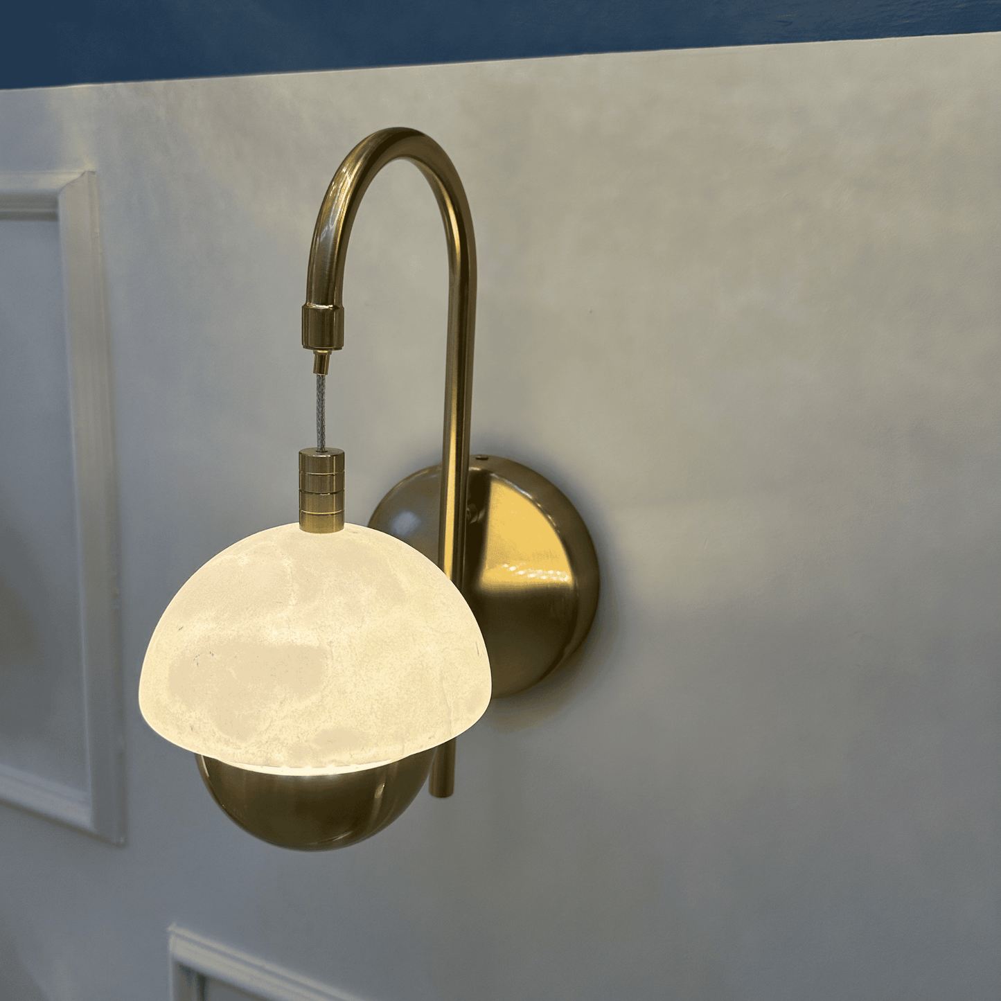 Modern marble sconce with brass backplate and warm glowing dome.