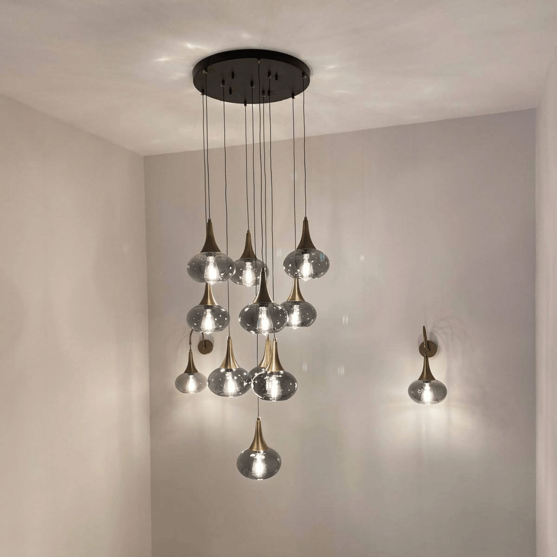 Multi-light pendant installation with glass globes and brass accents in a modern staircase.