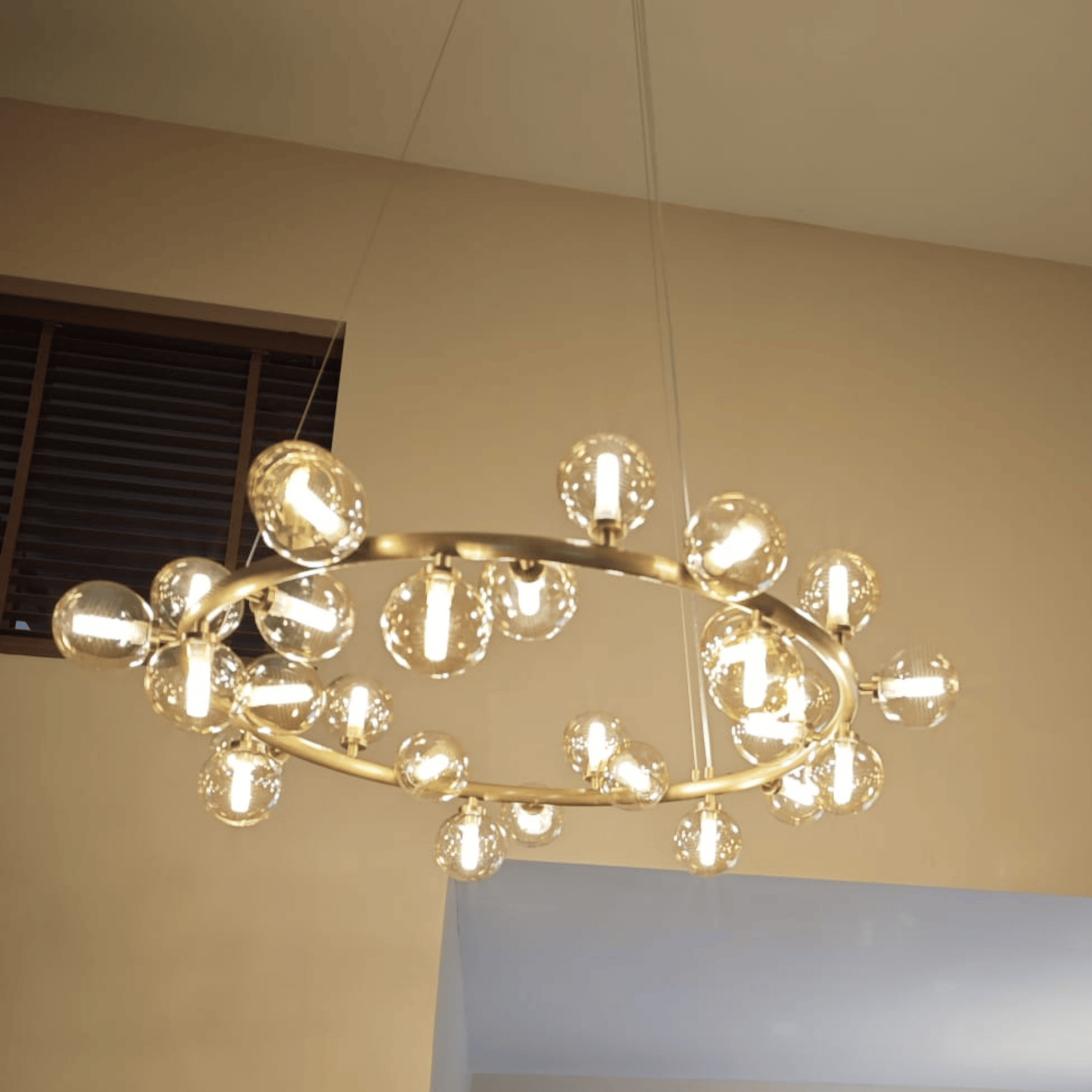 Suspended brass chandelier with clear globe bulbs, offering modern lighting in a clean interior design.