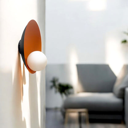 Wall-mounted sconce with burnt orange interior and opal globe bulb in a modern living space with natural light
