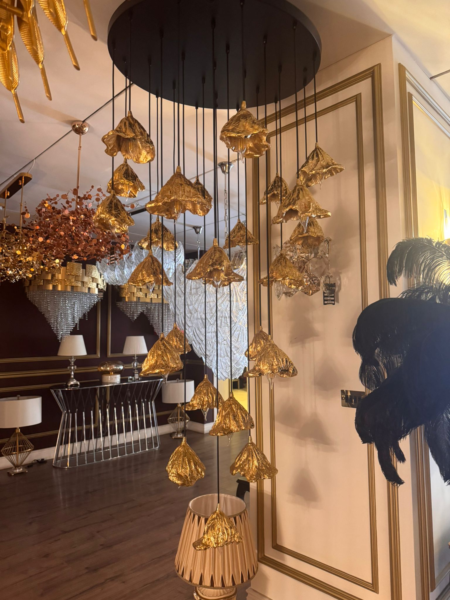 Multi-tiered pure brass leaf pendant lights hanging in a high-end showroom interior.