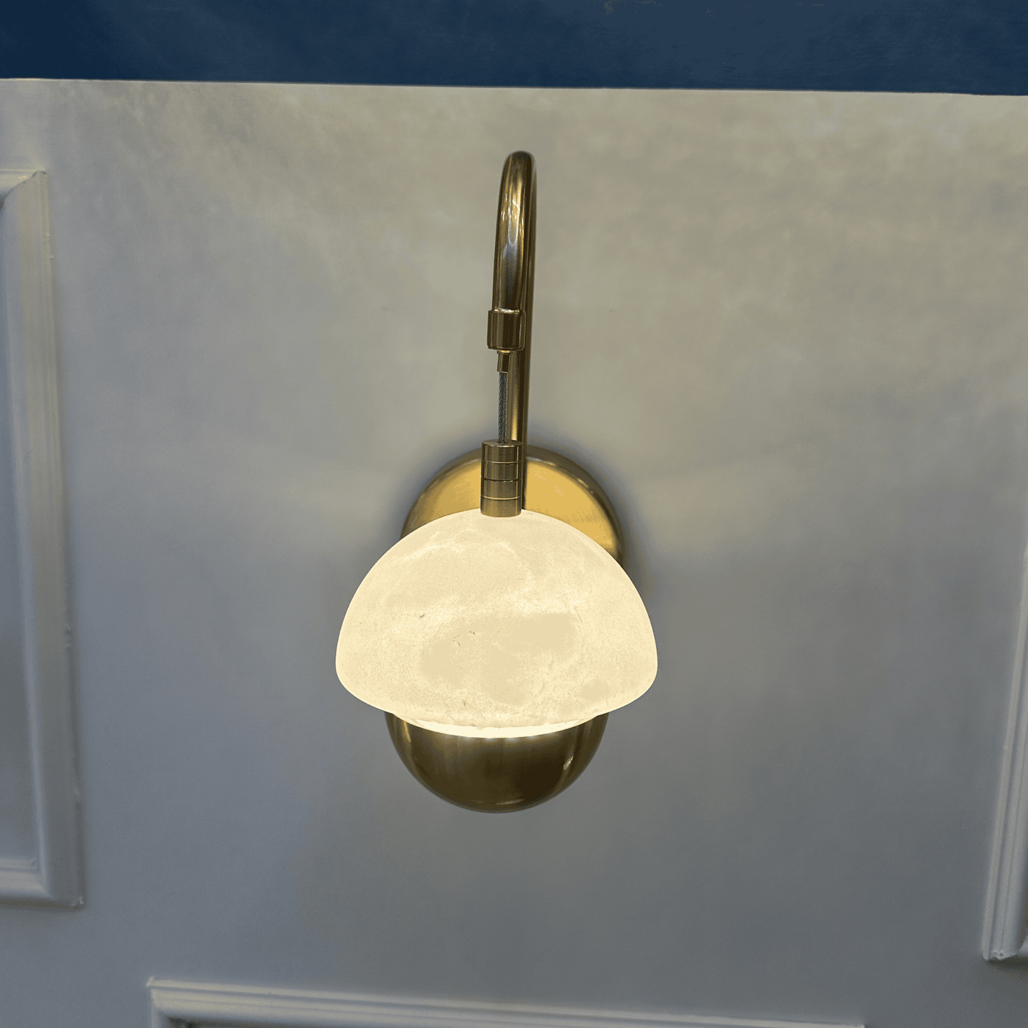 Overhead view of marble sconce with a brass mount and softly glowing dome.